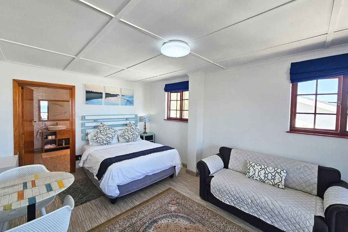 A spacious bedroom featuring a neutral color palette, timber-framed windows, and an en-suite bathroom, offering a comfortable and functional living space.