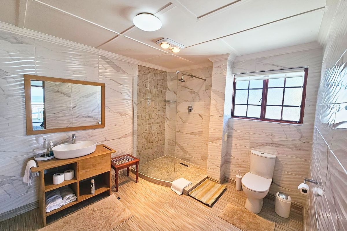 Modern bathroom featuring a walk-in glass shower, vessel sink vanity, and tiled walls with contemporary finishes.