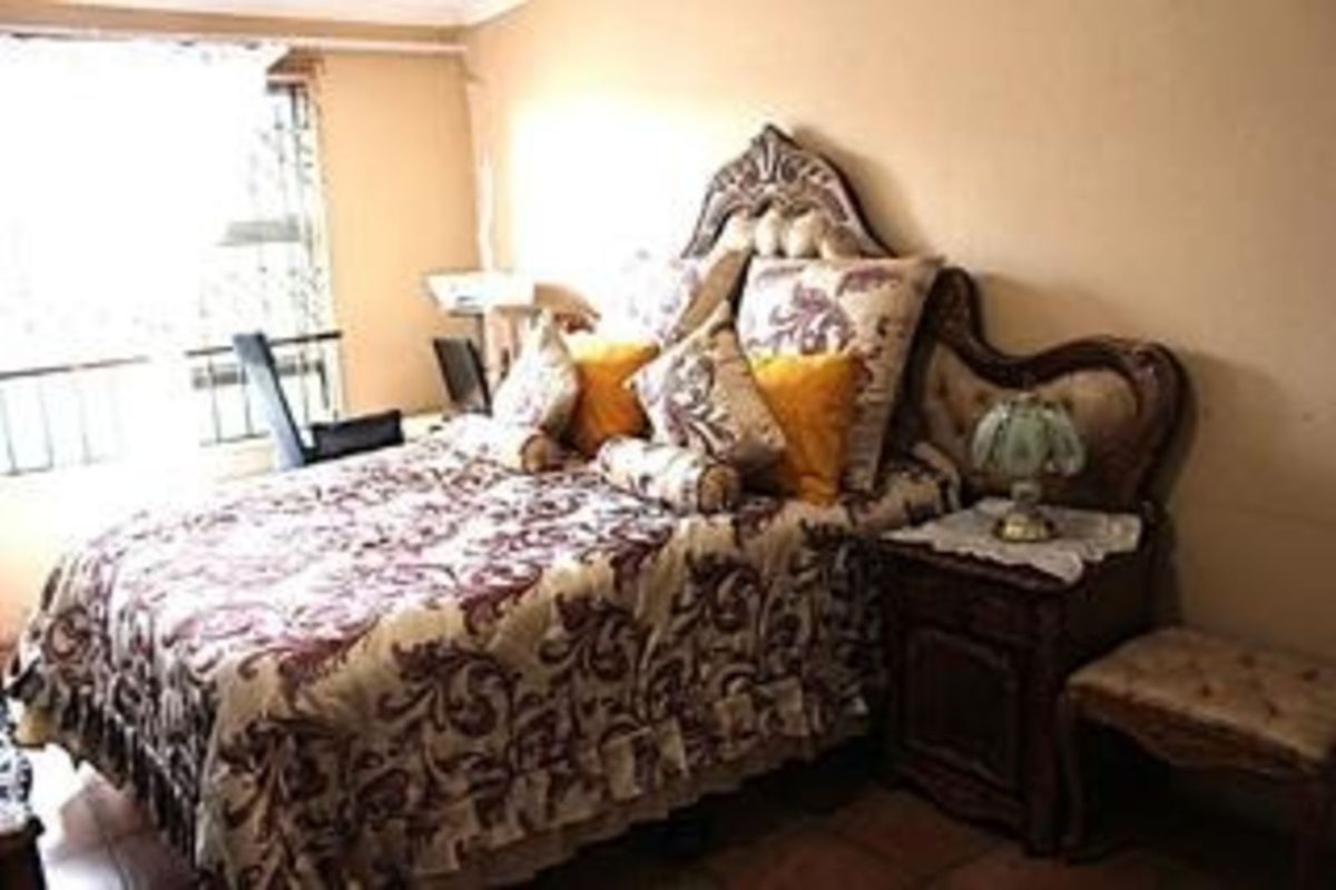A bedroom featuring tiled flooring and a window with security bars, providing natural light to the space.