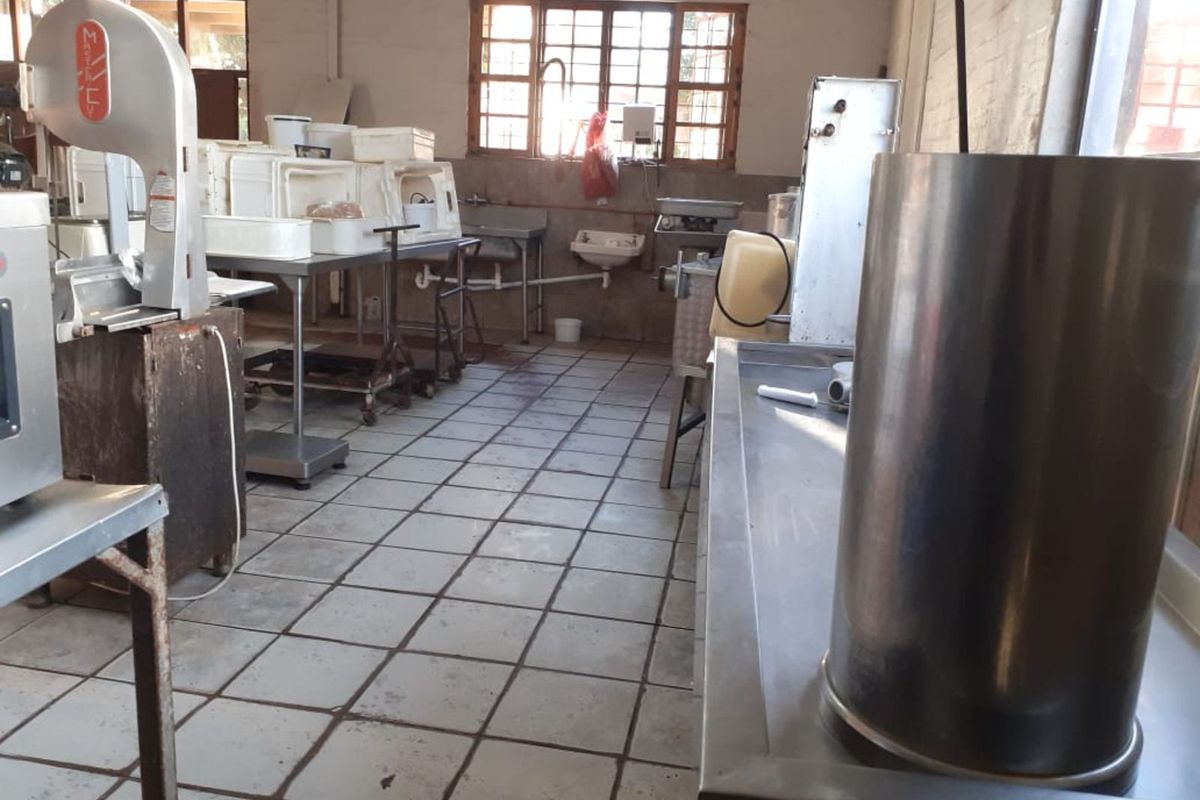 A functional commercial kitchen space featuring industrial stainless steel work surfaces, tiled flooring, and multiple prep stations with integrated plumbing fixtures.