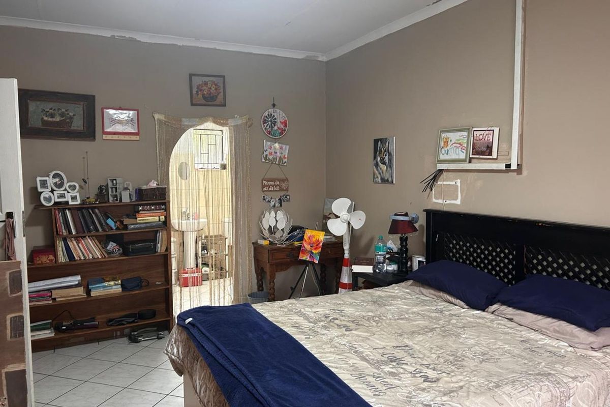 A bedroom featuring tiled flooring and an arched doorway leading to an en-suite bathroom area.