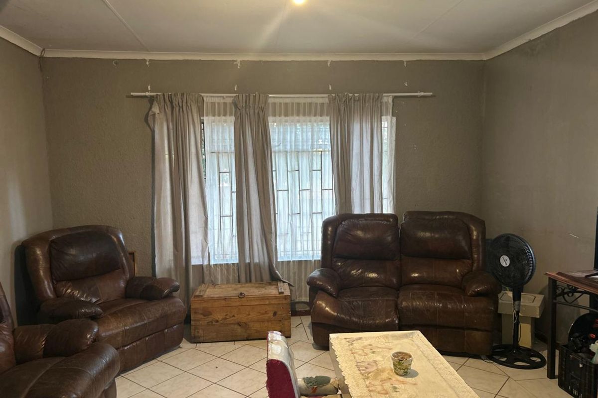 A living room featuring tiled flooring, textured walls, and security bars on the windows.