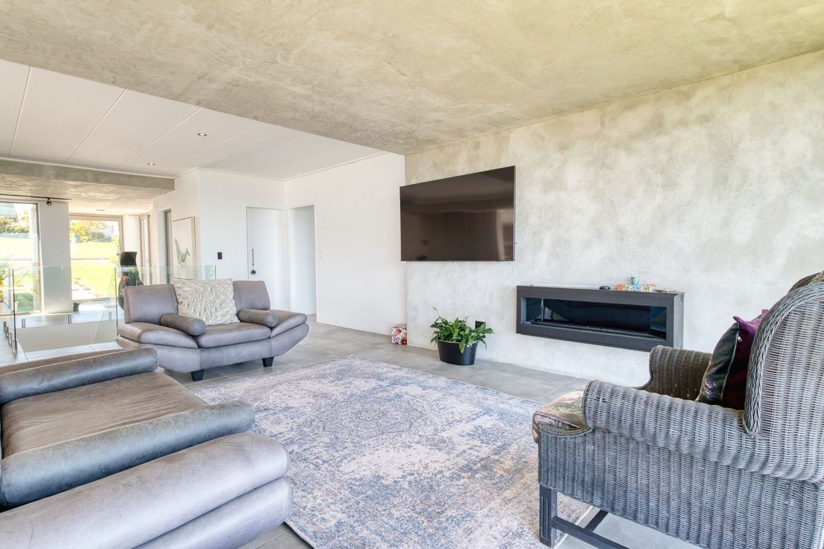 Modern living room featuring a textured concrete feature wall, built-in linear fireplace, and large format floor tiles with an open-plan layout.