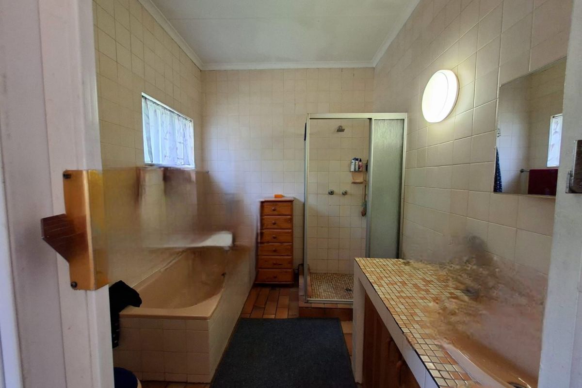 A dated bathroom featuring a built-in bathtub, a separate shower enclosure, and a tiled vanity area with integrated cabinetry.
