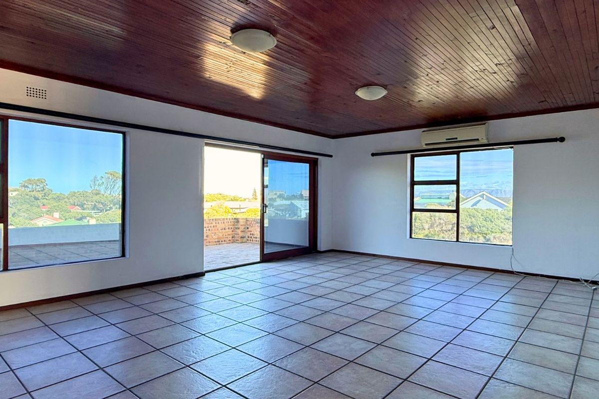 Spacious living area featuring tiled flooring, a timber-paneled ceiling, large windows for natural light, and direct access to an outdoor balcony.