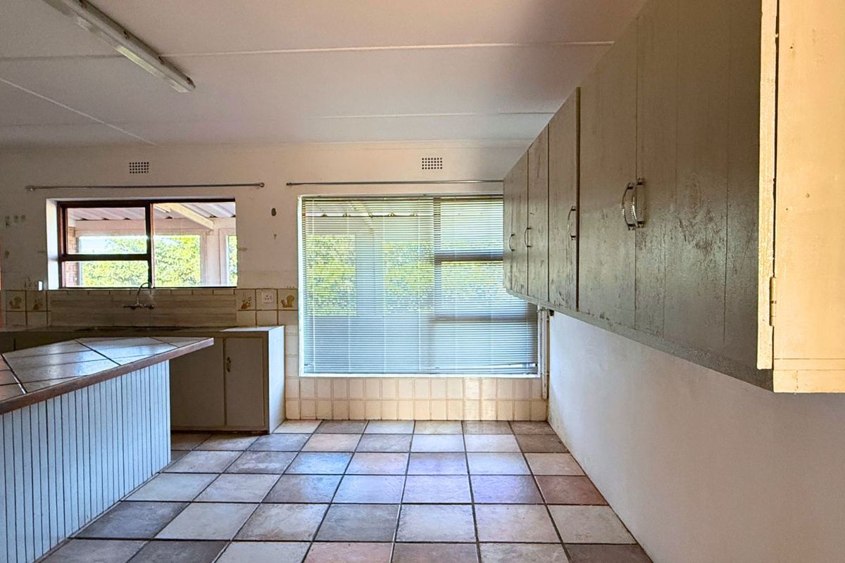 A dated kitchen area featuring tiled flooring, built-in cabinetry, and a breakfast counter, offering a blank canvas for renovation and modernization.