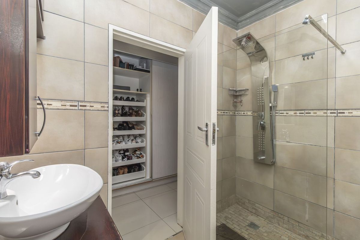Bathroom featuring a glass-enclosed shower with a modern shower panel, vessel sink vanity, and direct access to a built-in walk-in closet.