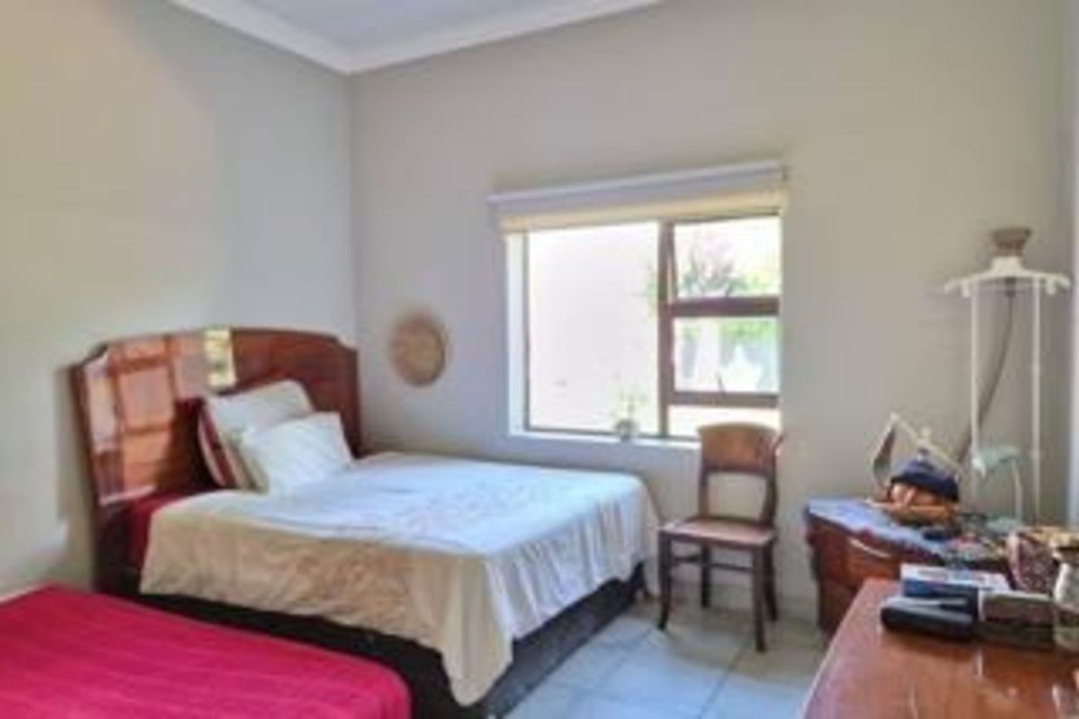 A bedroom featuring tiled flooring, neutral wall finishes, and a large window providing natural light.