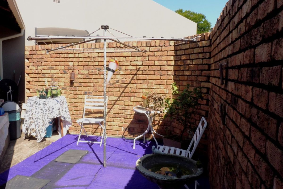 A private rear courtyard featuring exposed brick boundary walls and a paved area, providing a secluded outdoor space for the townhouse.