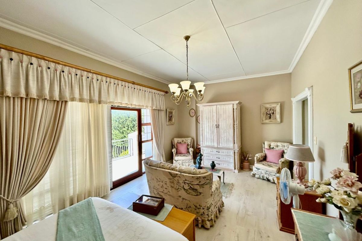 Spacious bedroom featuring light-toned flooring, a classic chandelier, and direct access to a private balcony through sliding glass doors.