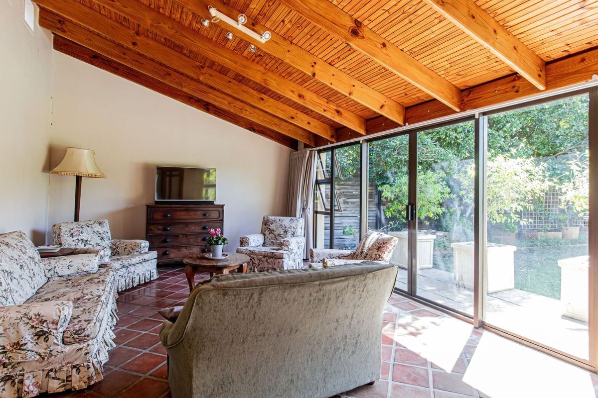 Spacious living room featuring exposed timber beam vaulted ceilings, terracotta tiled flooring, and large sliding glass doors providing seamless access to the garden.