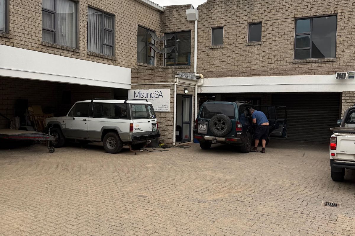 Industrial property exterior featuring a paved courtyard, covered parking bays, and brick facade construction.