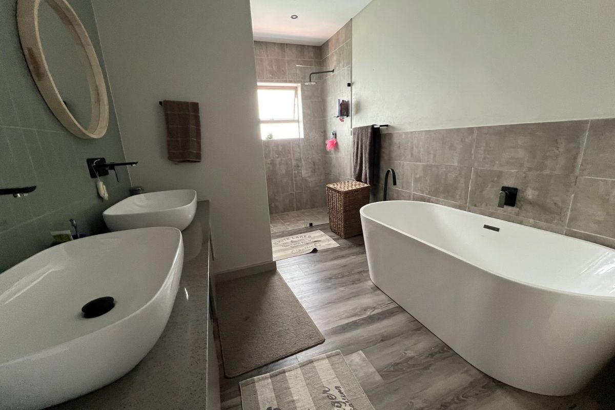Modern bathroom featuring a double vanity with vessel sinks, a freestanding bathtub, and a walk-in shower with tiled walls and wood-look flooring.