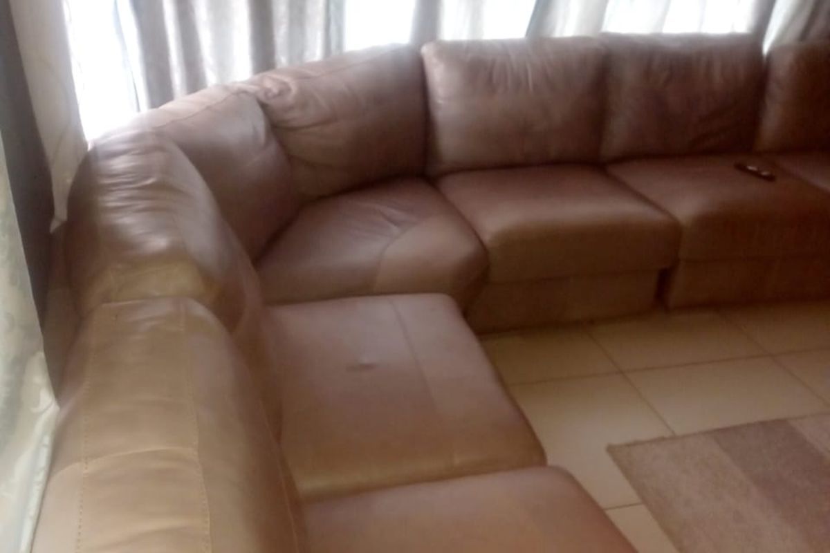 A living room area featuring tiled flooring and large windows with curtains, providing a bright and functional space.