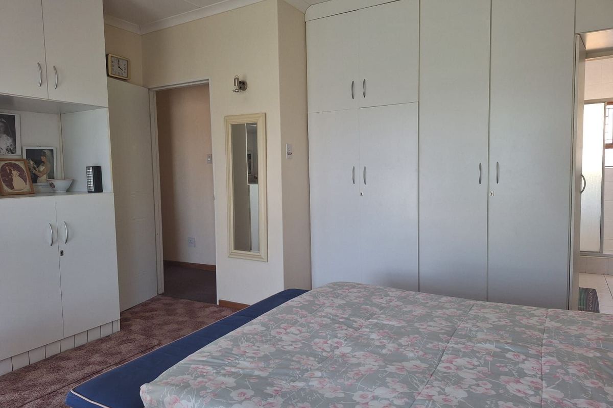 A bedroom featuring extensive built-in white cabinetry and wardrobes, providing ample storage space with direct access to an adjoining bathroom.