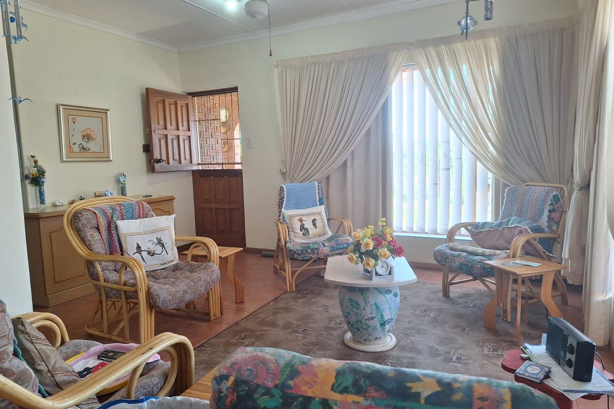 A comfortable living room featuring tiled flooring, a ceiling fan, and large windows with curtains, providing a bright and functional space.
