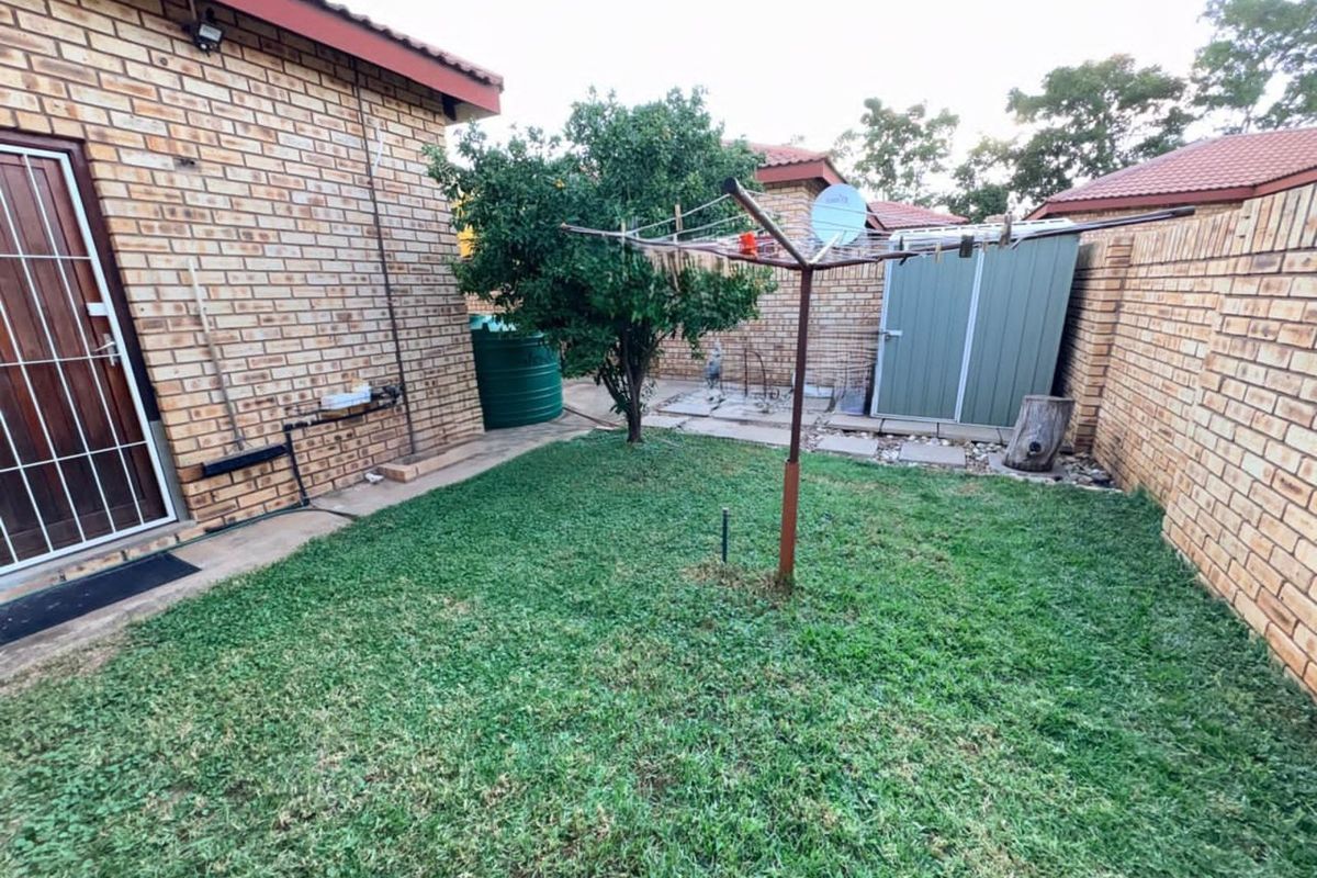 A private rear garden featuring a brick-walled perimeter, a small storage shed, a water tank, and a rotary clothesline.