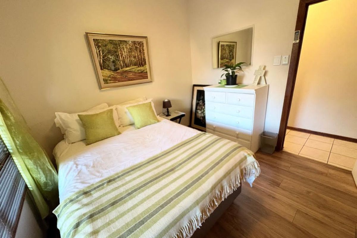 A cozy bedroom featuring wood-look flooring and neutral wall finishes, providing a comfortable and functional sleeping space.