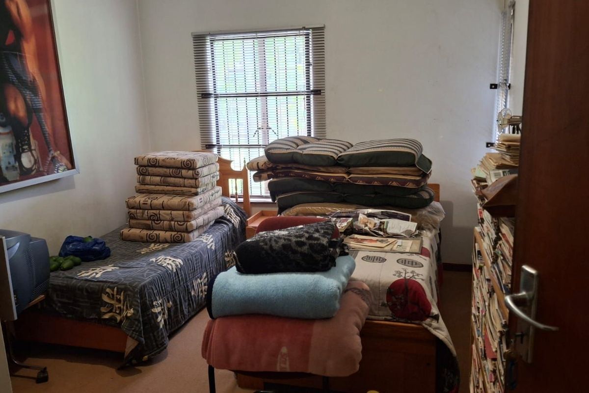 A bedroom featuring two single bed frames and a window with fitted venetian blinds.