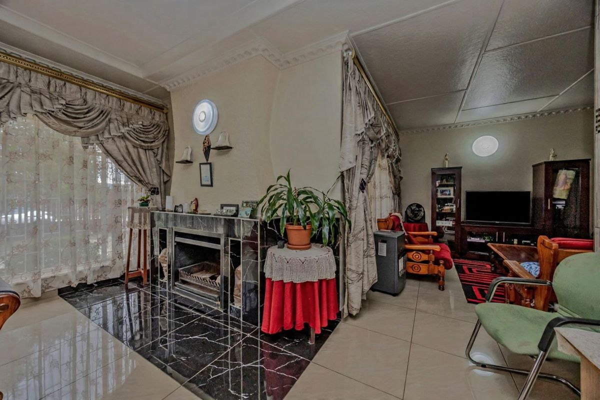 Living room featuring a central fireplace with marble-style surround, tiled flooring, and decorative ceiling cornicing.