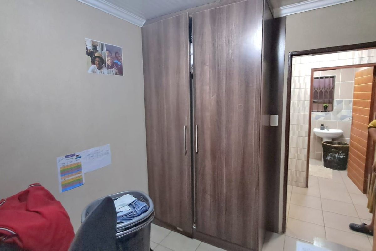 A bedroom featuring a built-in wooden wardrobe with a doorway leading to an adjacent tiled bathroom.