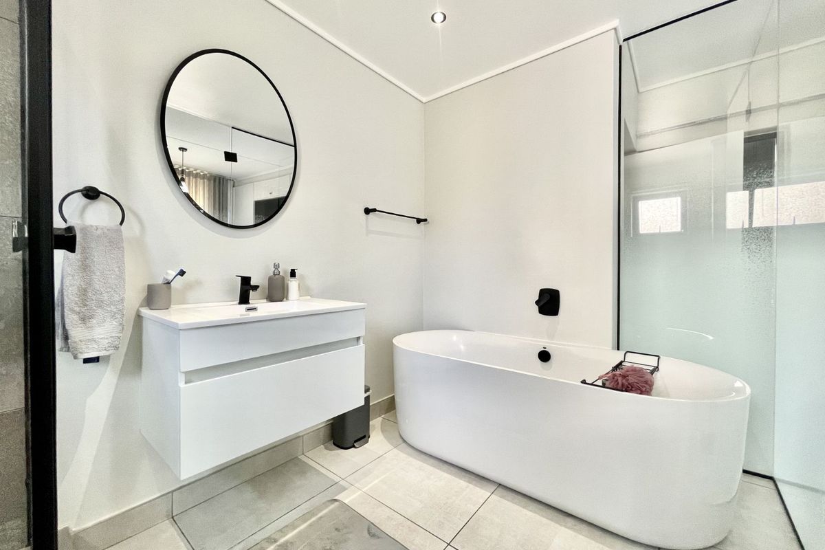 Modern bathroom featuring a sleek wall-mounted vanity, a contemporary freestanding bathtub, and a glass-enclosed shower with matte black fixtures.