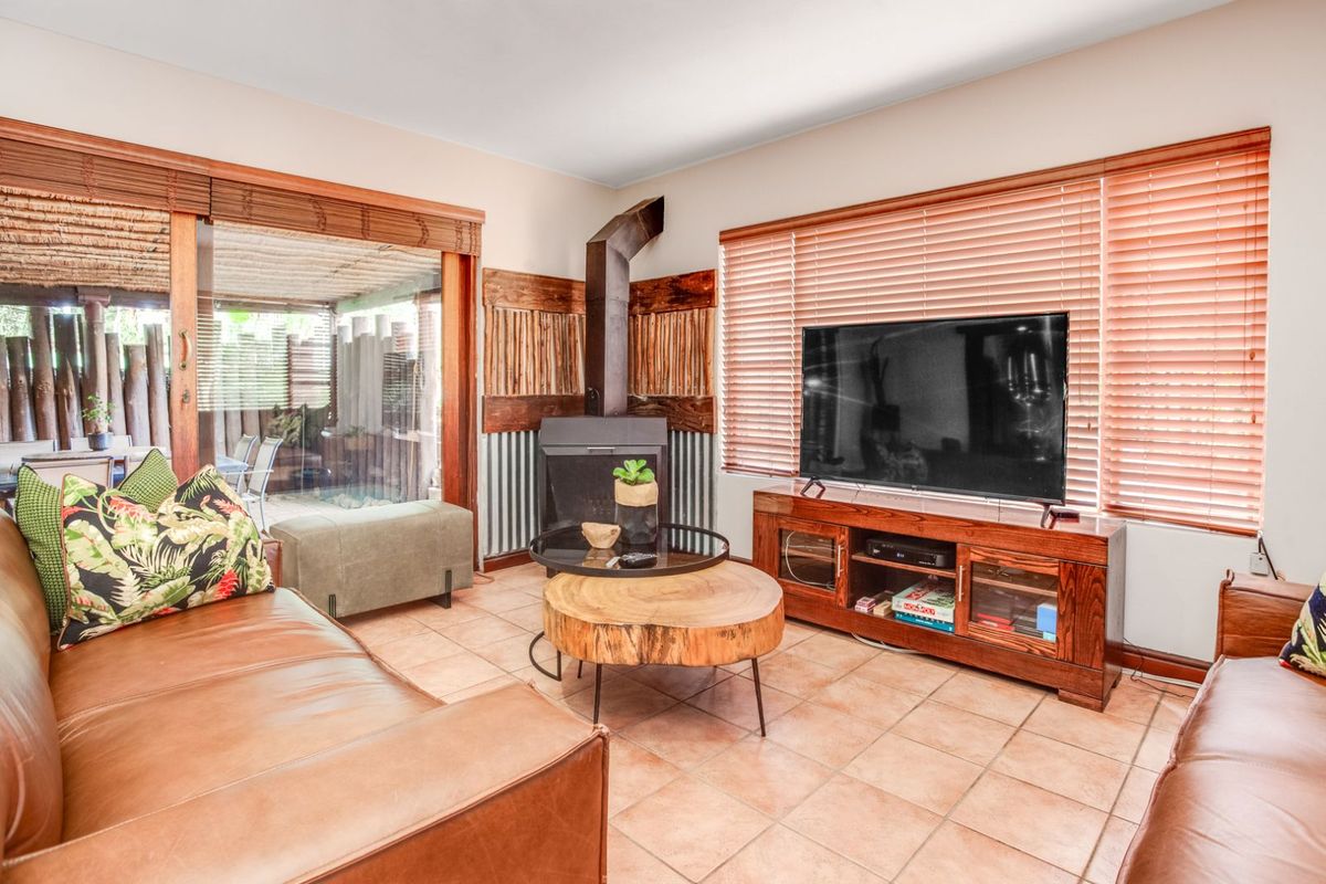 A cozy living room featuring a built-in fireplace with a metal flue, tiled flooring, and large sliding doors providing access to an outdoor patio area.