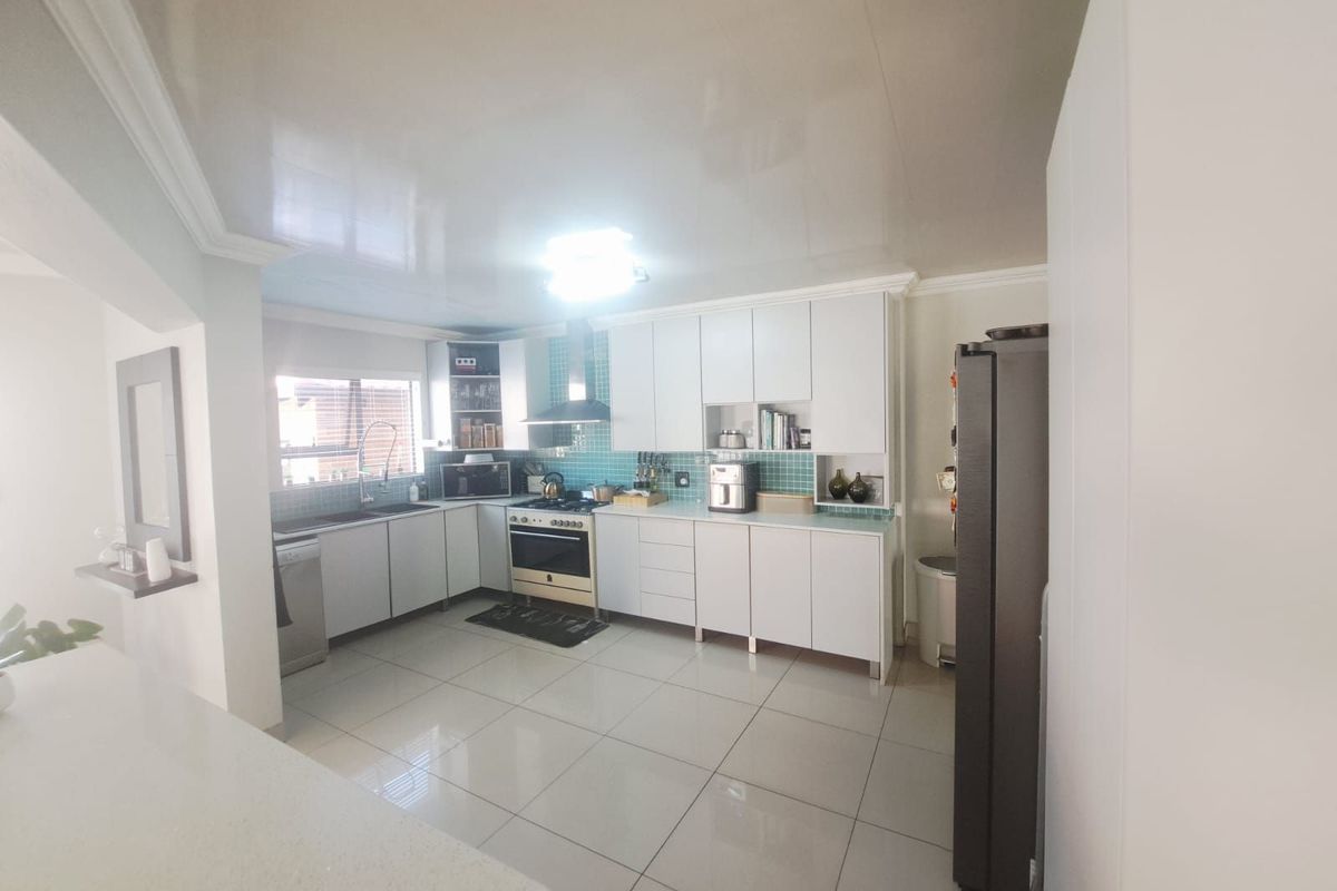 A functional kitchen featuring white cabinetry, a tiled backsplash, a built-in stove with extractor fan, and polished floor tiles.
