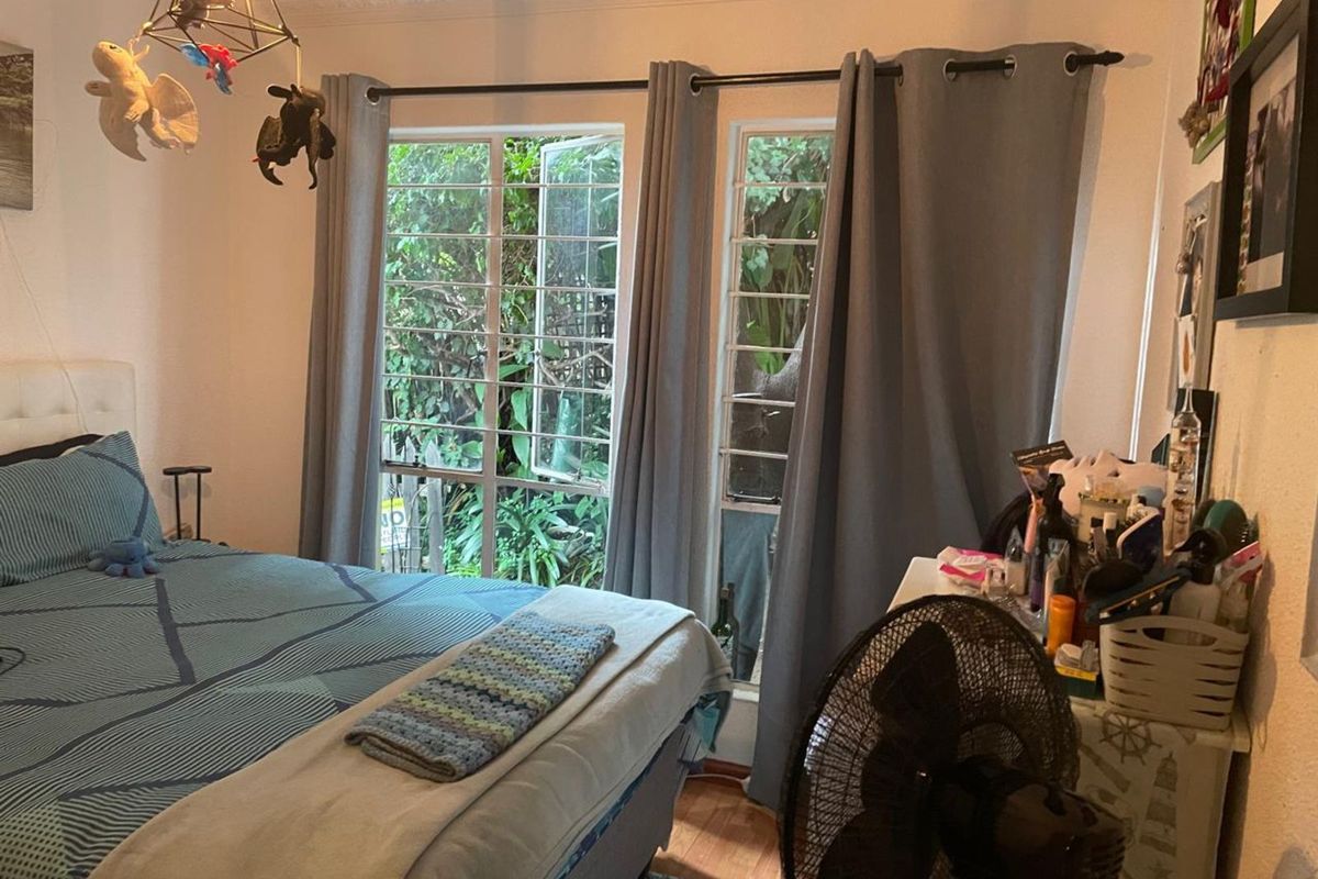 A bedroom featuring large windows with security bars, crown molding, and wooden flooring.