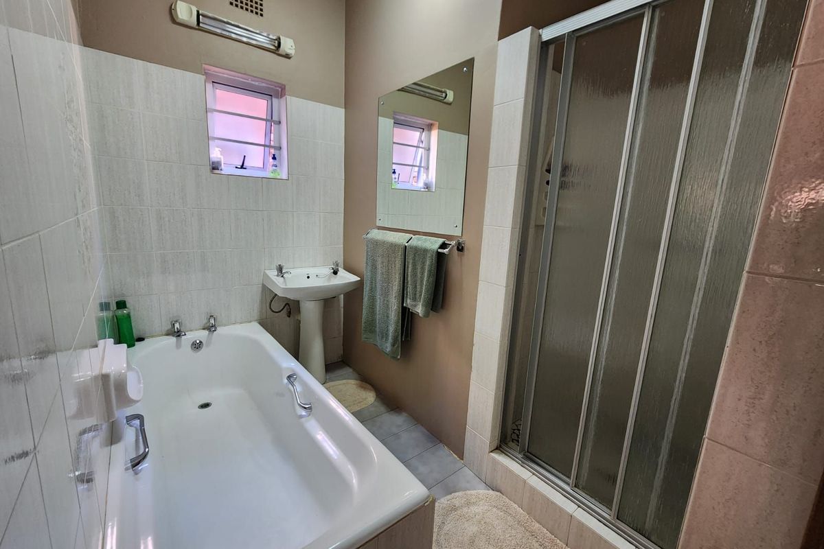 A functional bathroom featuring a white bathtub, pedestal basin, and a separate shower enclosure with a glass door.
