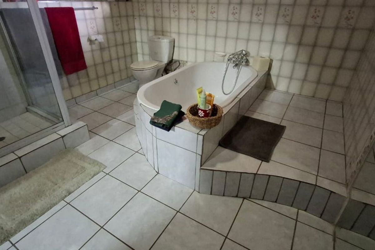 A functional bathroom featuring a built-in bathtub, a separate glass-enclosed shower, and tiled flooring throughout.