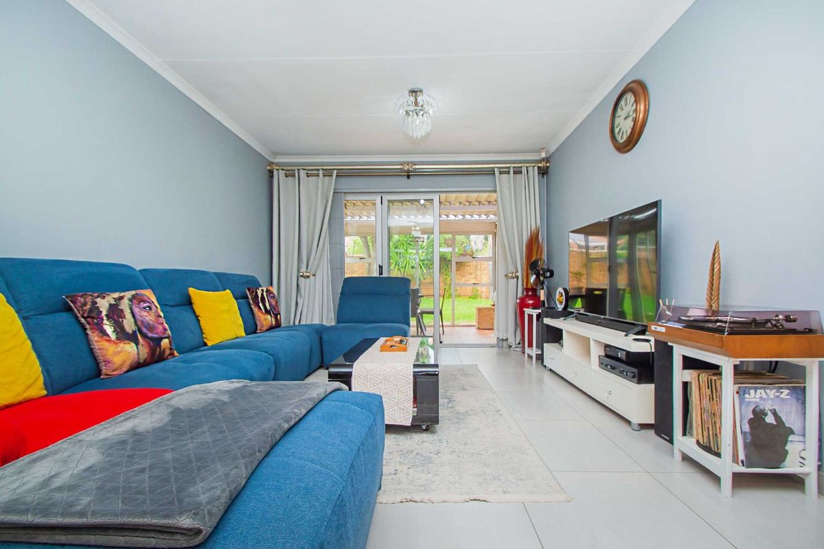 A bright and inviting living room featuring tiled flooring, neutral wall tones, and sliding glass doors that provide seamless access to the outdoor patio area.