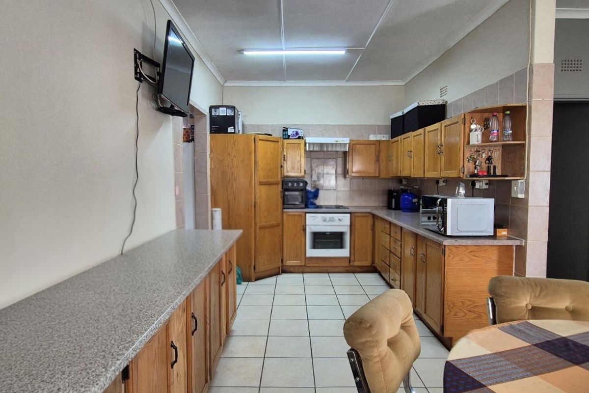 A functional kitchen featuring wooden cabinetry, tiled flooring, and built-in oven and hob, offering a practical layout for daily meal preparation.