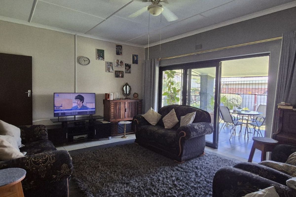 A comfortable living room featuring large sliding glass doors that open onto a covered patio, providing natural light and seamless indoor-outdoor flow.