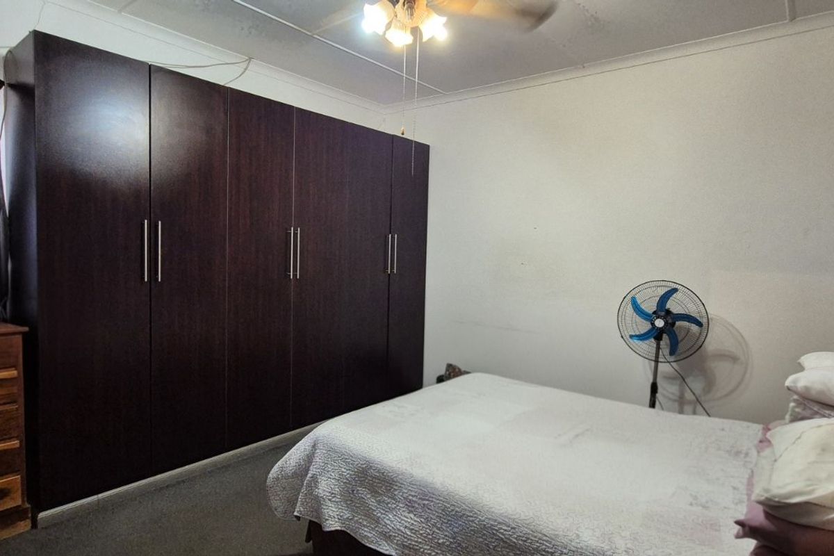 A bedroom featuring built-in dark wood cabinetry, a ceiling fan, and neutral wall finishes.