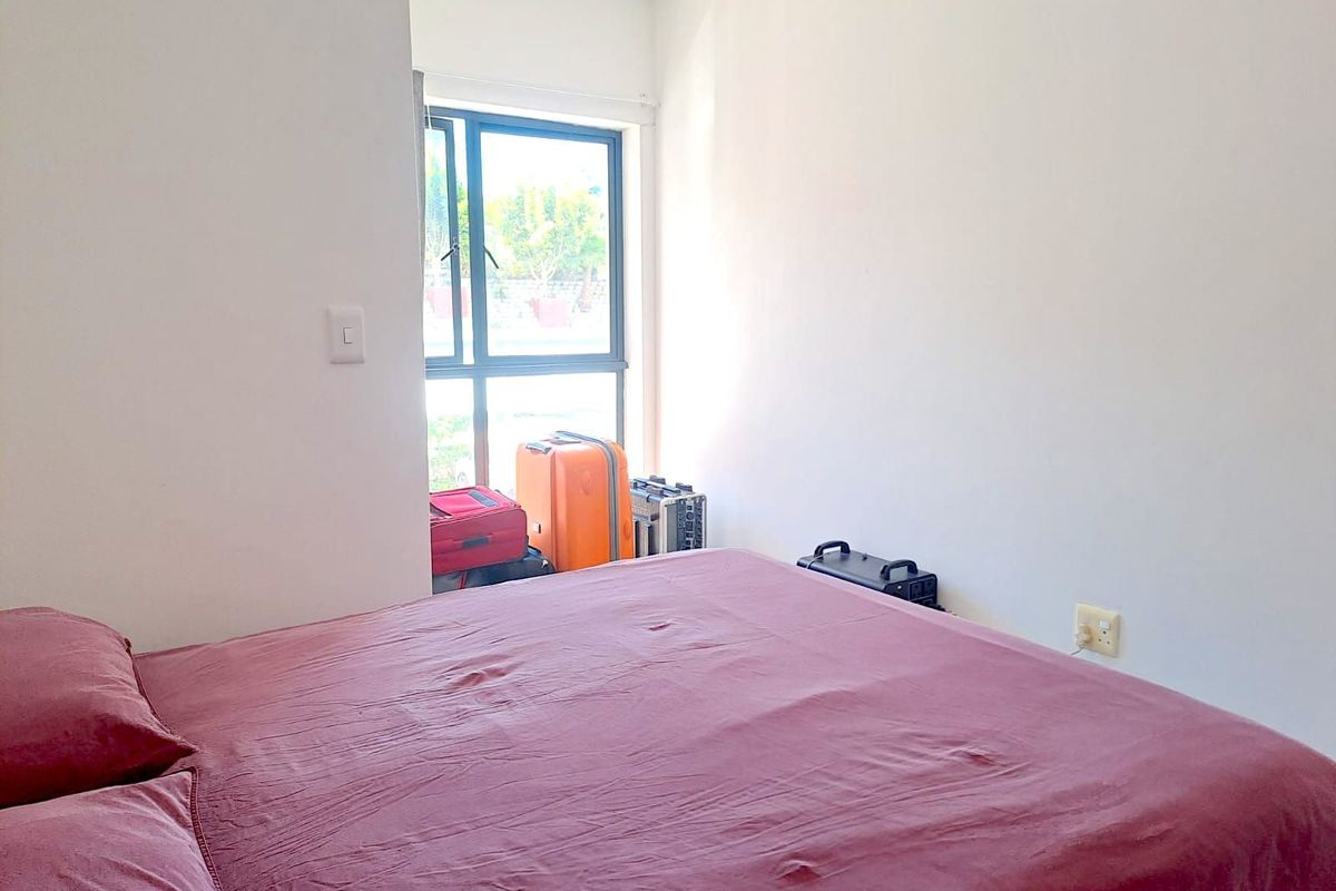 A simple bedroom featuring a window with natural light and standard electrical outlets.