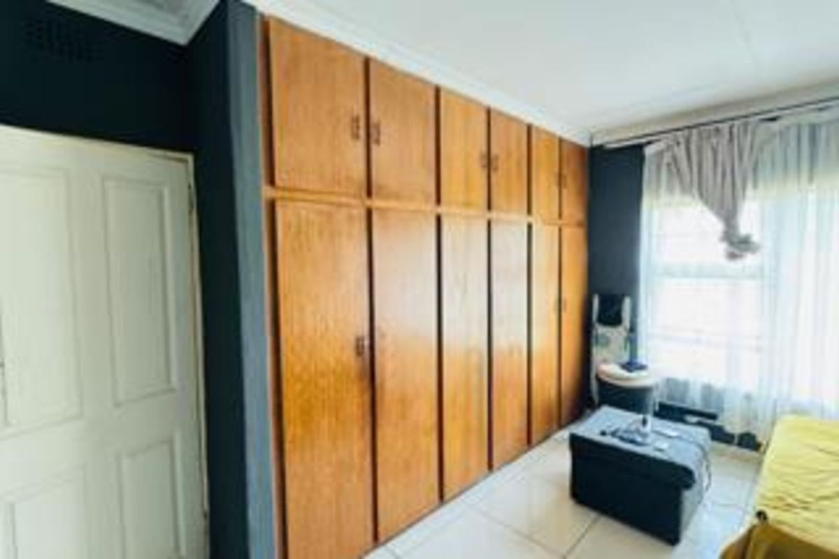 Bedroom featuring extensive floor-to-ceiling built-in wooden cabinetry and tiled flooring.