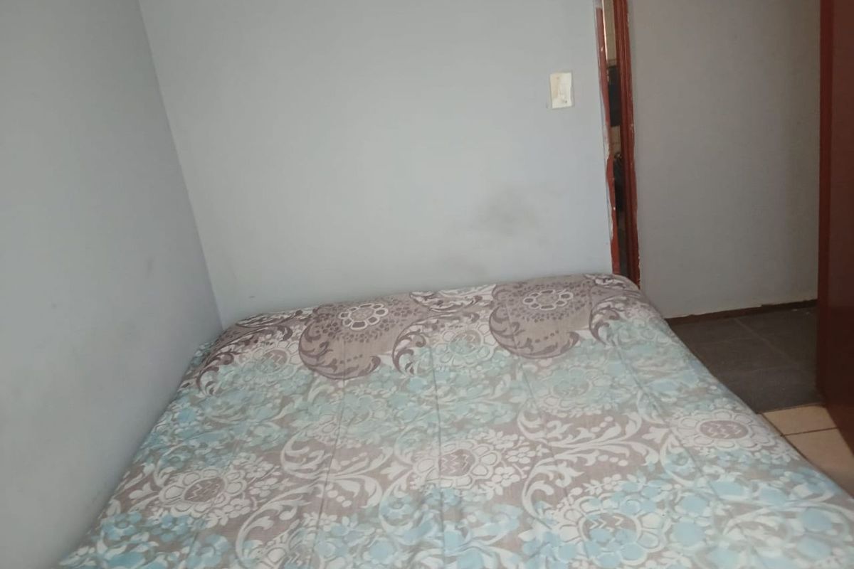 A compact bedroom featuring neutral wall tones and tiled flooring, providing a functional space for rest.