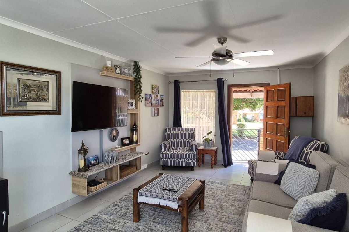 A comfortable living room featuring a built-in fireplace, ceiling fan, and direct access to the outdoor patio area.