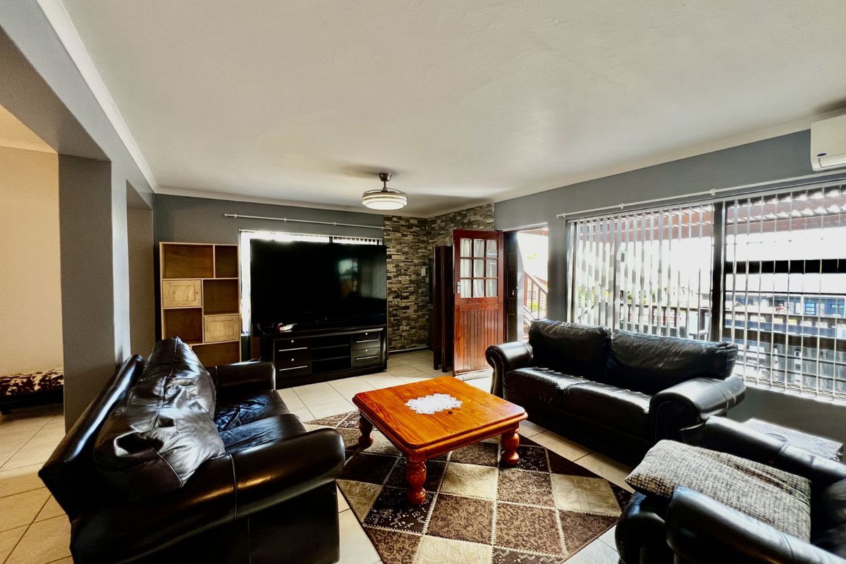 Spacious living room featuring tiled flooring, a stone-cladding feature wall, and direct access to an outdoor patio area.