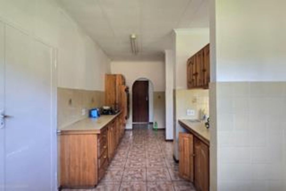 A dated kitchen featuring wooden cabinetry, tiled flooring, and tiled splashbacks, offering a functional layout with potential for modernization.