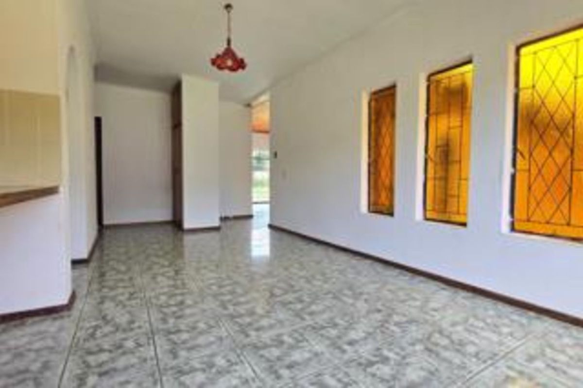 An empty living area featuring tiled flooring and distinctive stained glass windows, offering a blank canvas for potential interior updates.