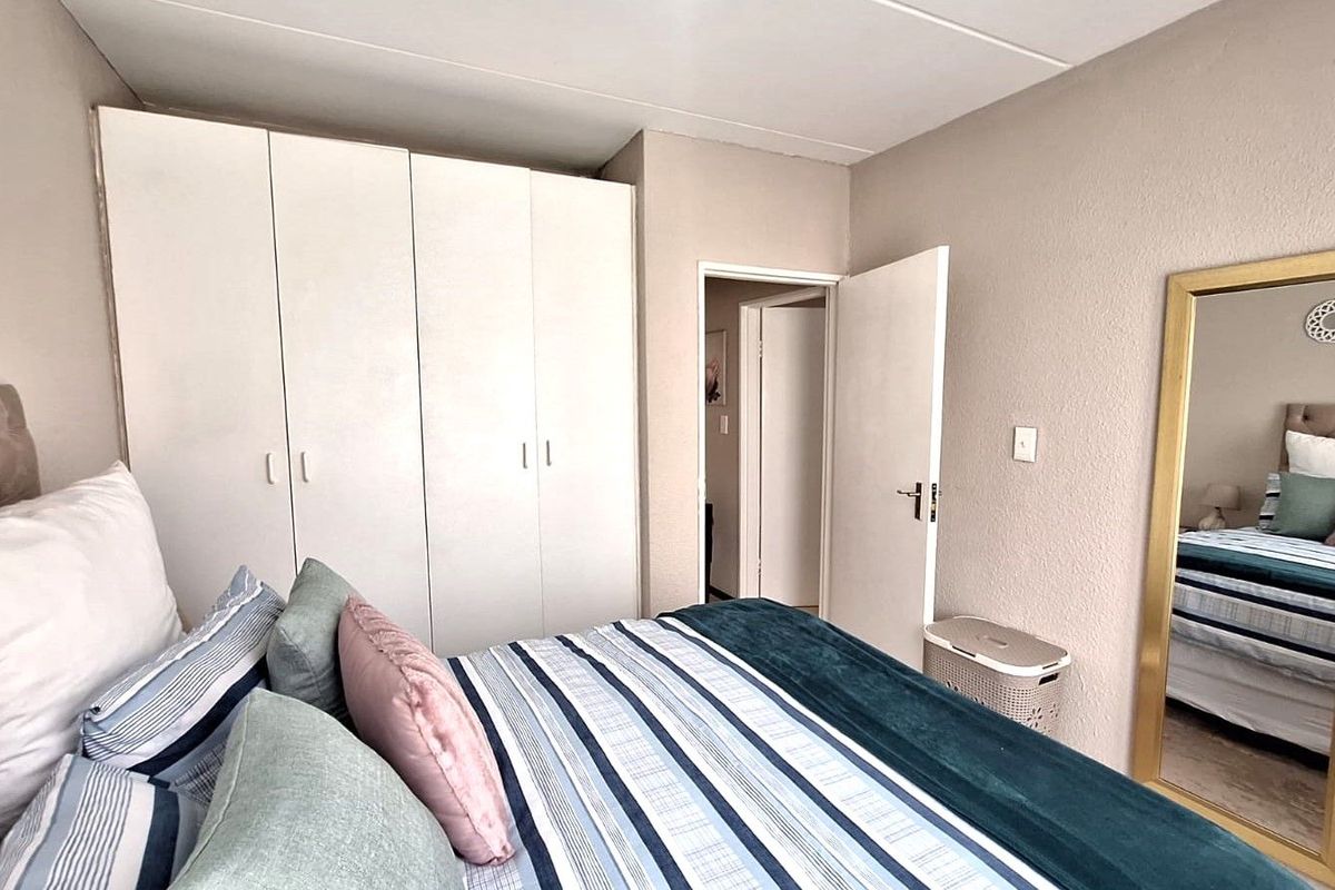 A functional bedroom featuring built-in white cabinetry, neutral wall finishes, and a standard doorway leading to the hallway.