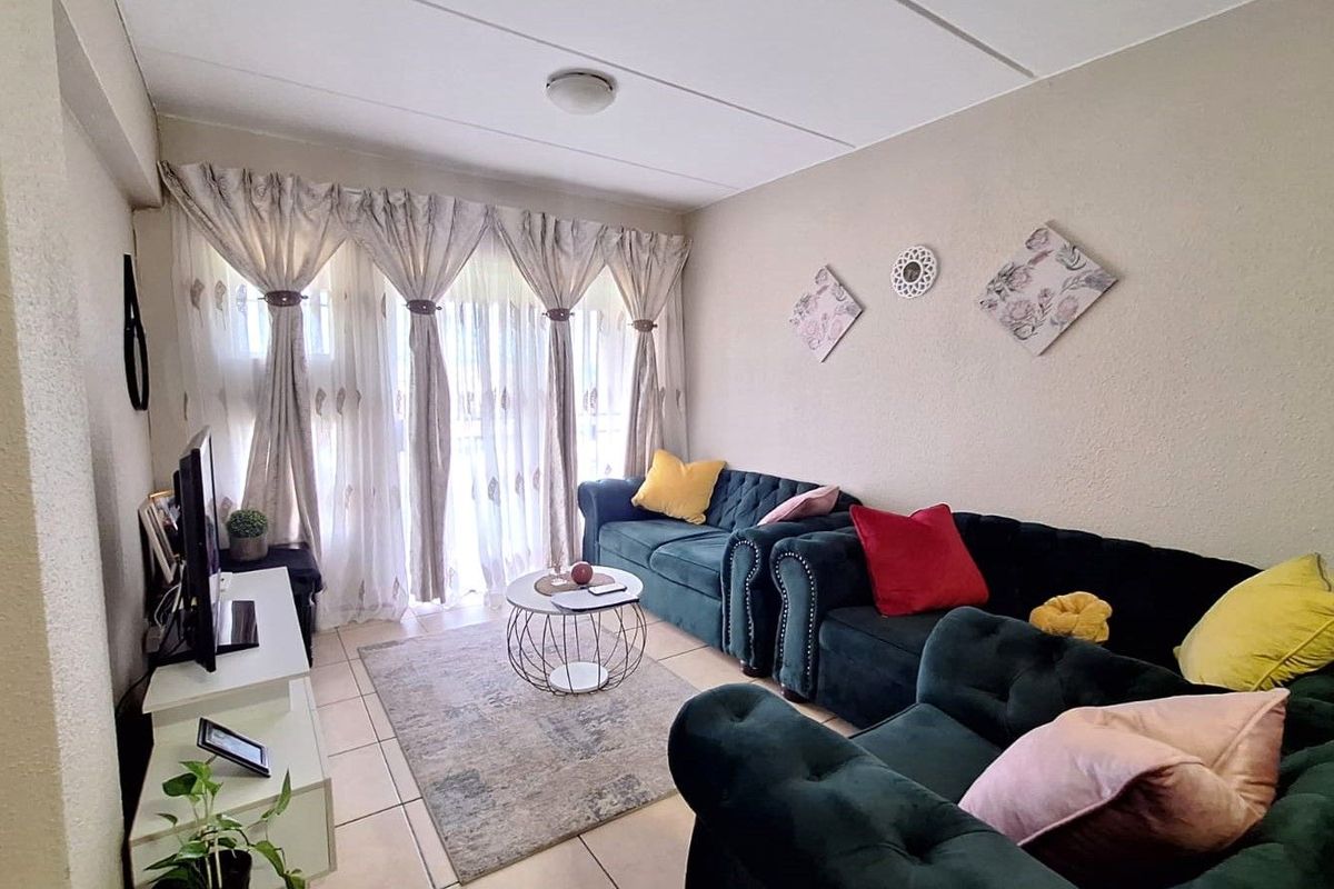A comfortable living room featuring tiled flooring and large sliding glass doors that provide access to the outdoor area.