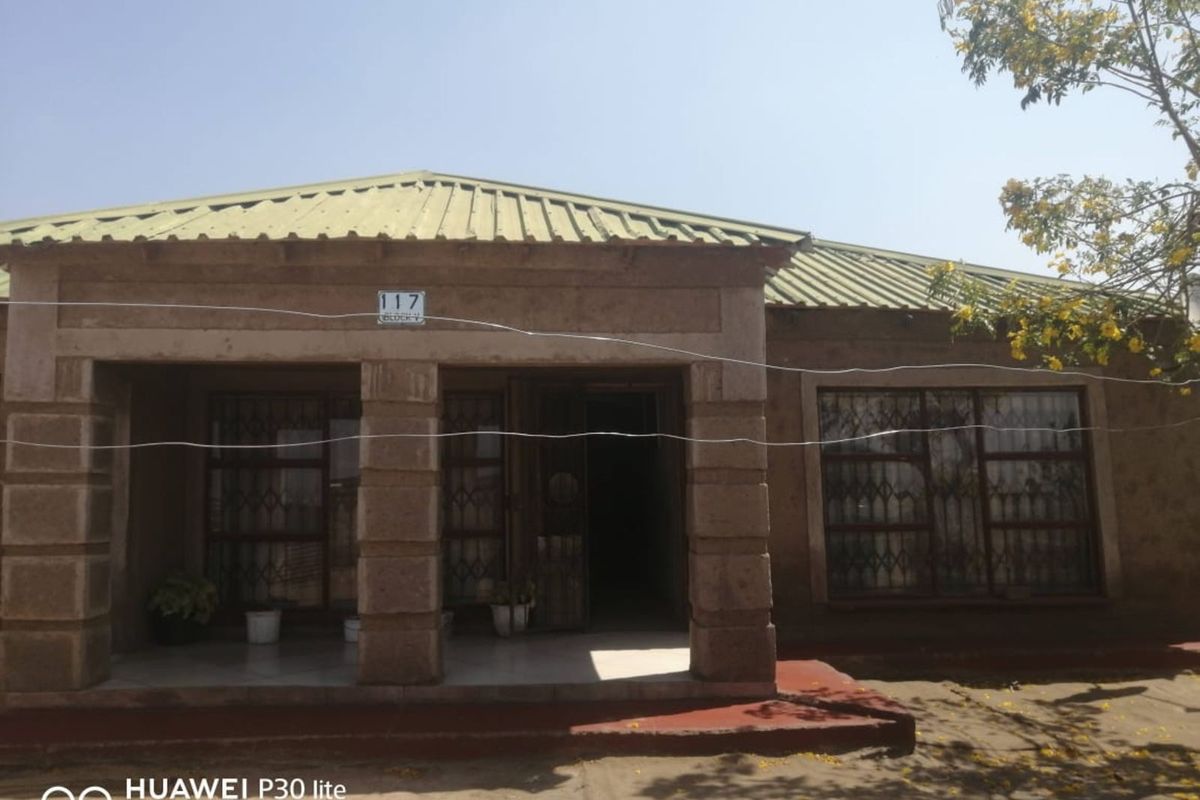 Front elevation of a single-story house featuring a covered entrance porch, metal security window grilles, and a pitched roof.