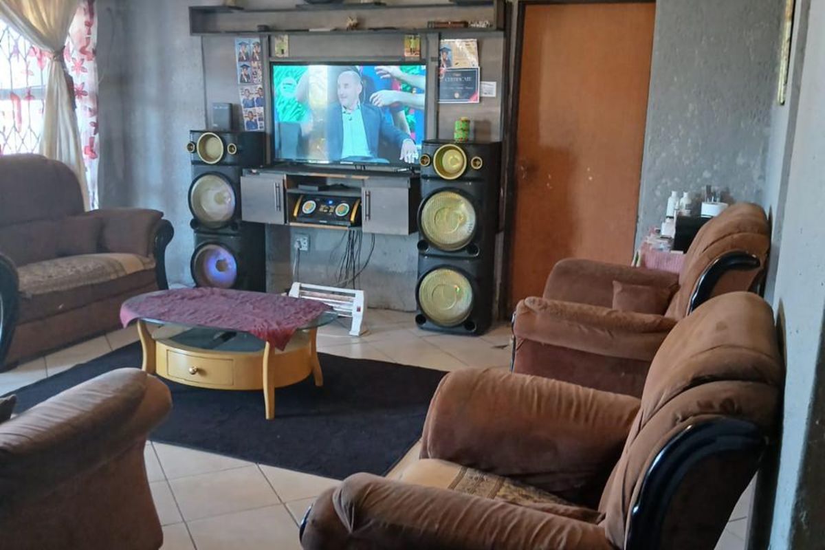 A living room featuring tiled flooring, a built-in media unit, and decorative ceiling paneling.