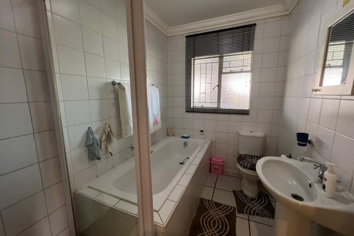 A functional bathroom featuring a built-in bathtub, a separate shower enclosure, a pedestal basin, and a toilet with white wall tiling.