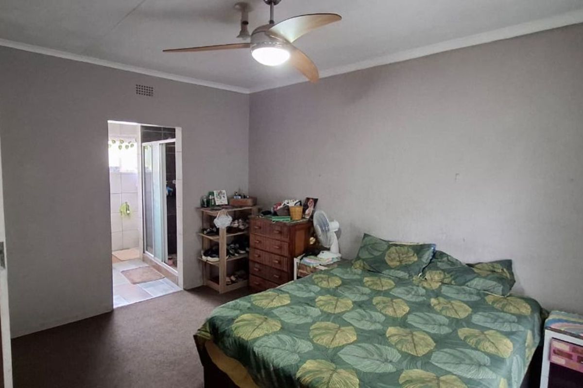 A bedroom featuring a ceiling fan and an en-suite bathroom with a shower enclosure.