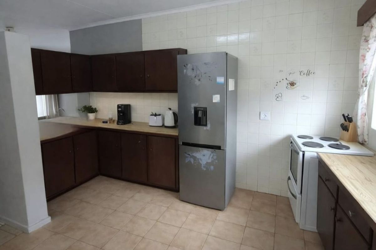 Functional kitchen featuring dark wood cabinetry, light-toned laminate countertops, tiled flooring, and a tiled splashback wall.