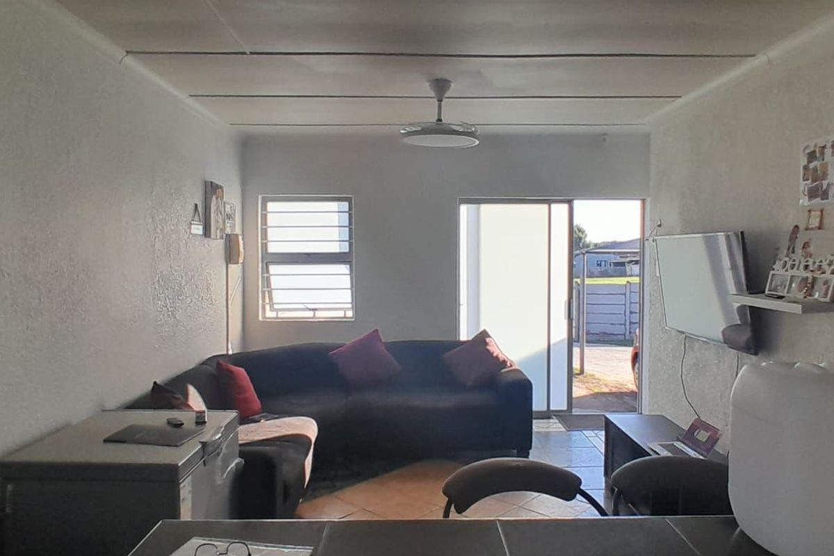 A living room area featuring tiled flooring, a ceiling fan, and a sliding door providing access to the exterior.